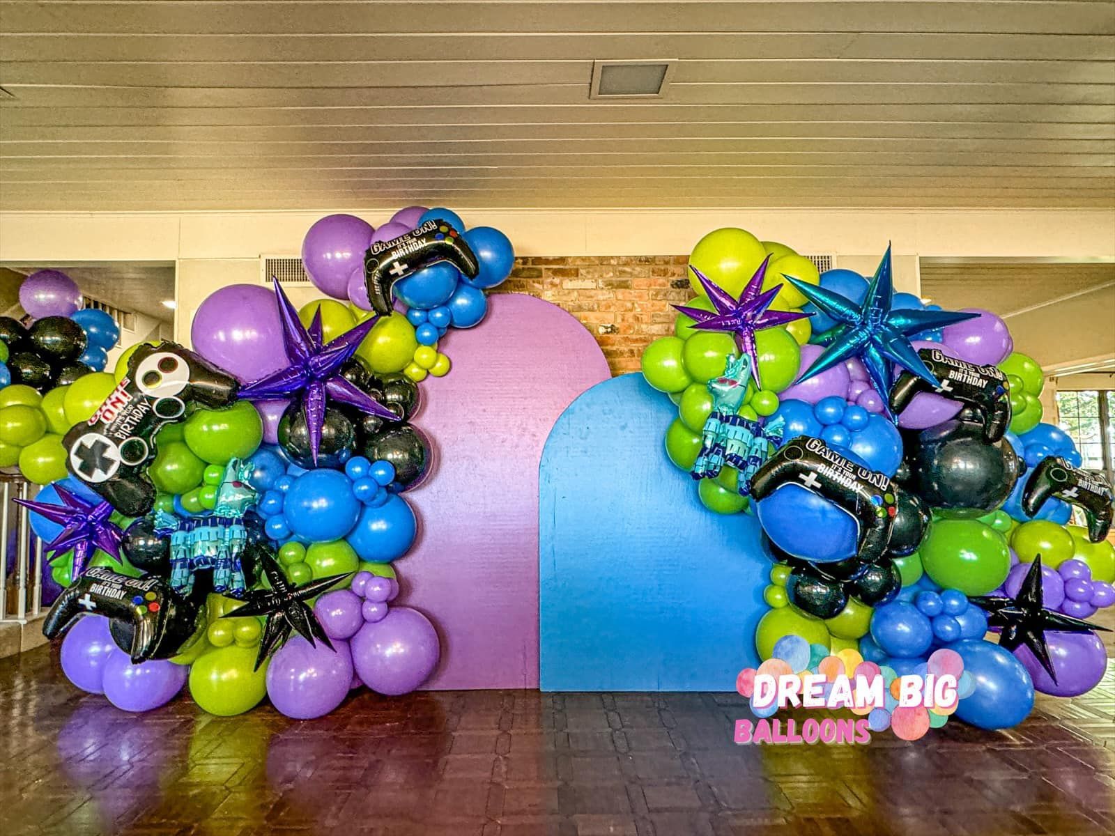 A bunch of balloons are sitting on a wooden floor in a room.