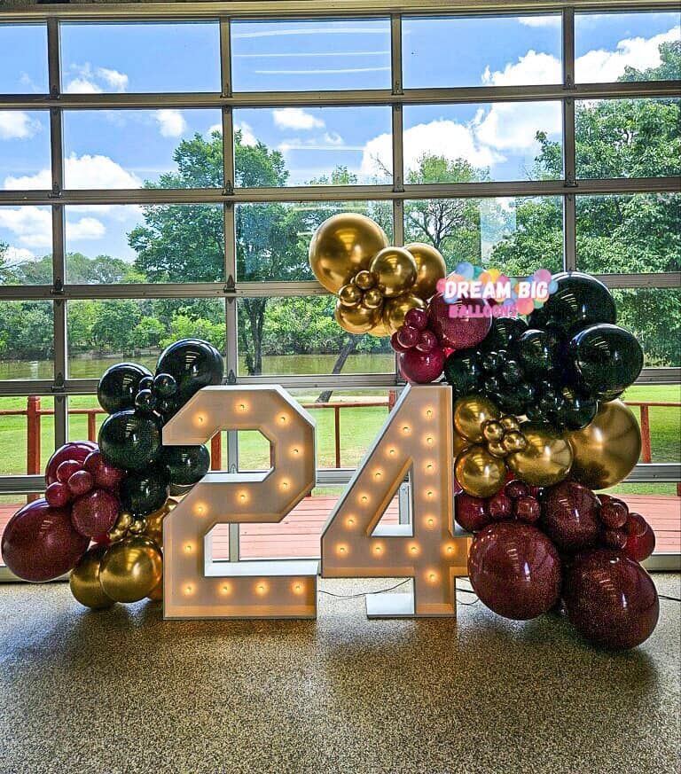 The number 24 is surrounded by balloons and lights.