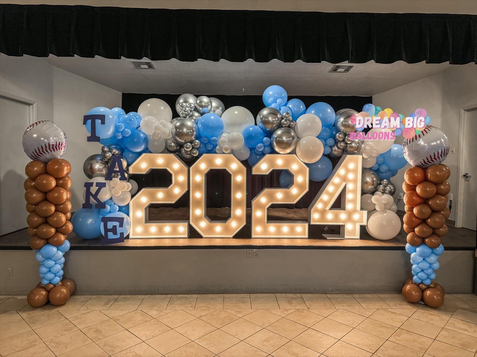 a stage is decorated with balloons and lights for a graduation party