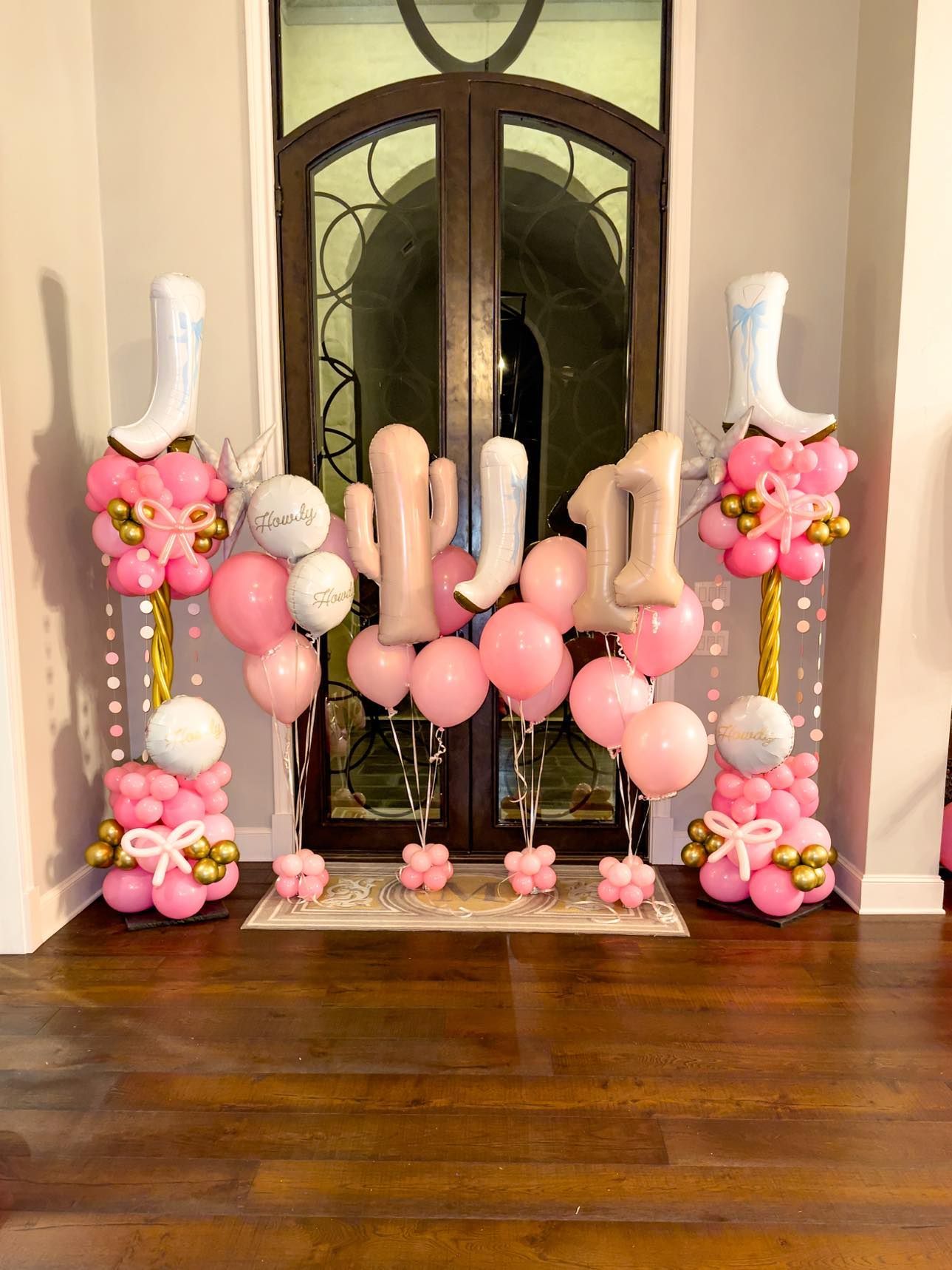 A room filled with pink and white balloons and cowboy boots.