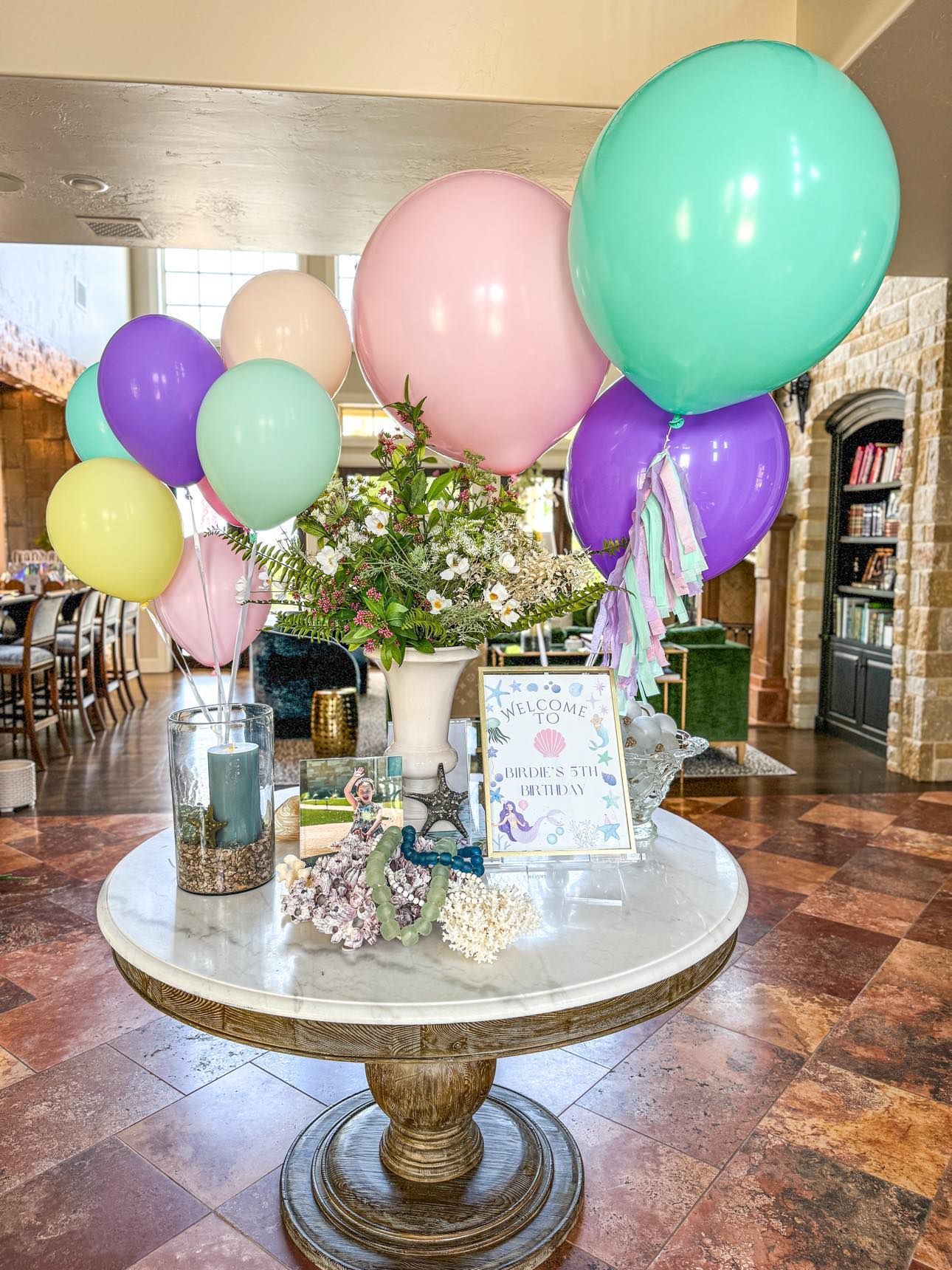 A table with balloons and flowers on it in a living room.