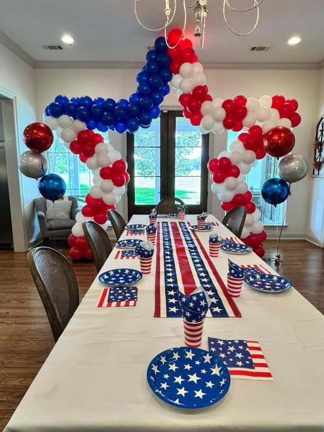A table is decorated with red , white and blue balloons for a fourth of july party.