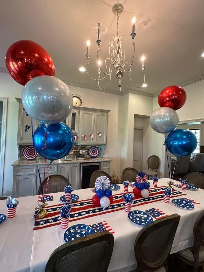 A table is decorated with red , white and blue balloons for a fourth of july party.