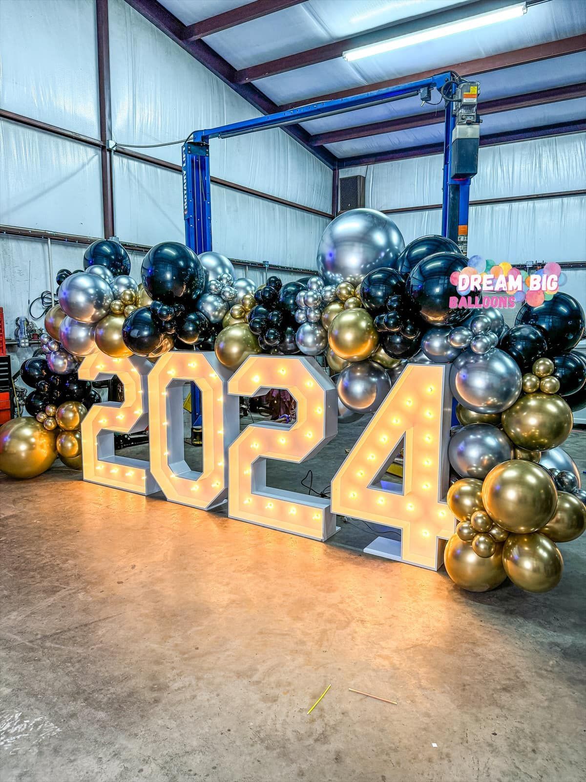 a large sign that says 2024 is surrounded by balloons in a garage