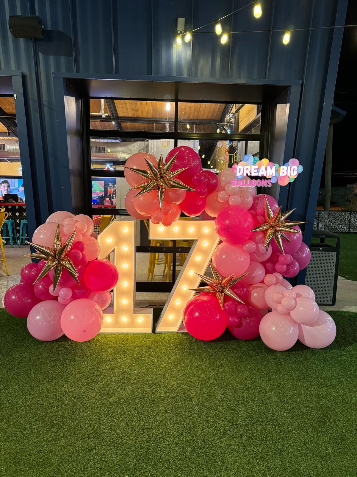 A large number 1 is surrounded by pink and gold balloons.