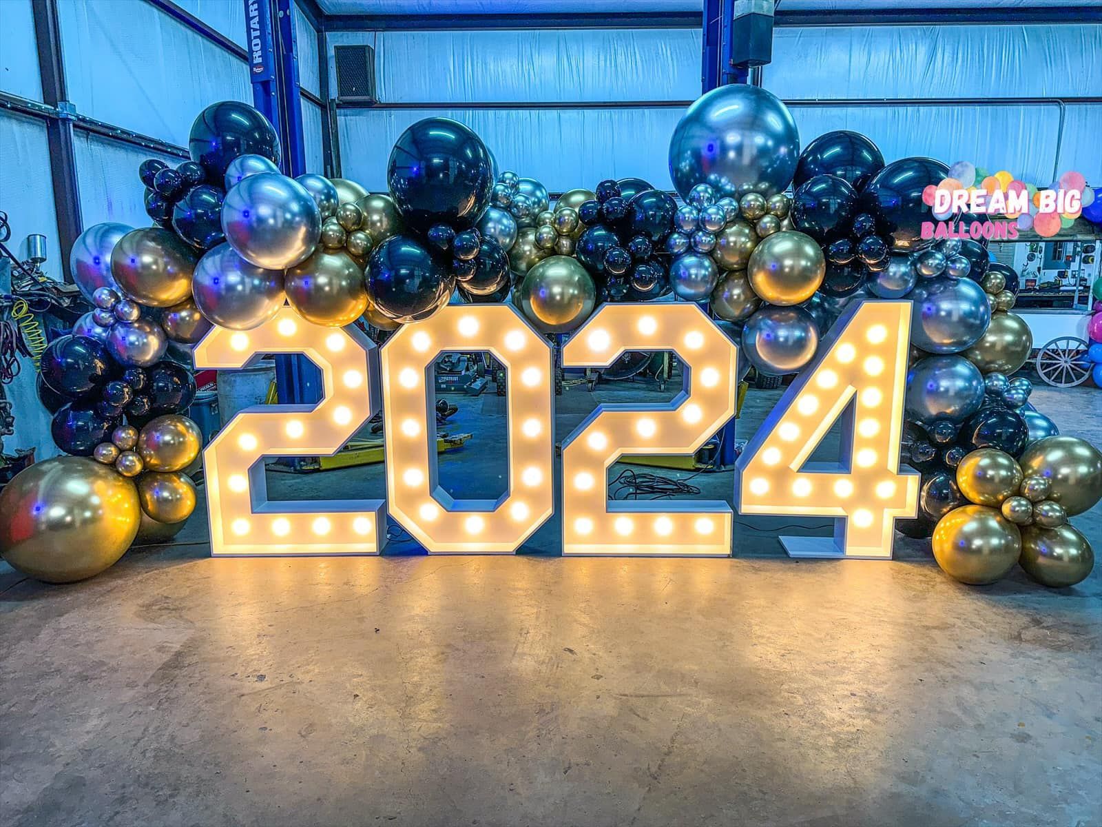 A large sign that says `` 2024 '' is surrounded by balloons and lights.