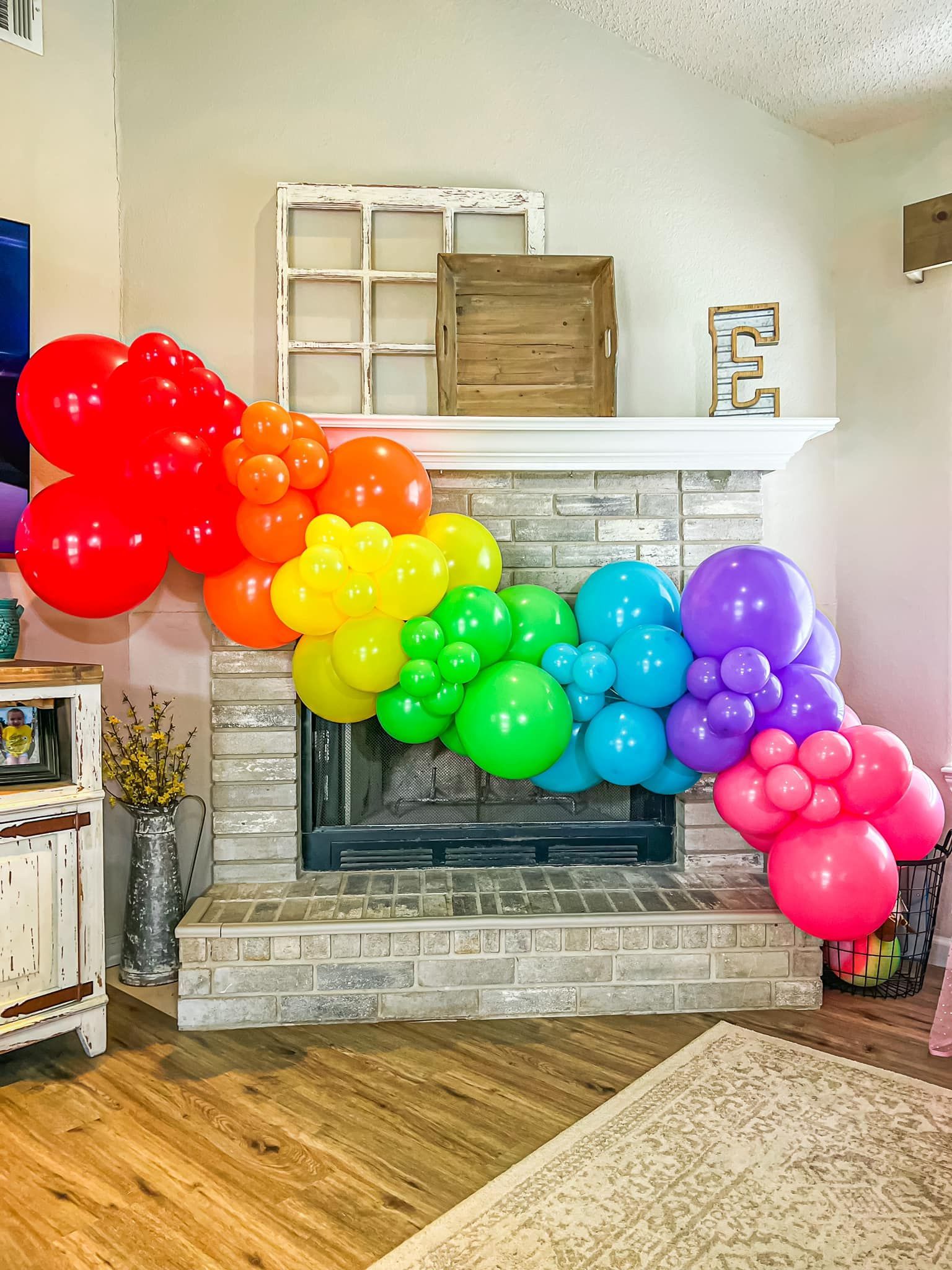 a living room with a fireplace decorated with balloons in the shape of a rainbow