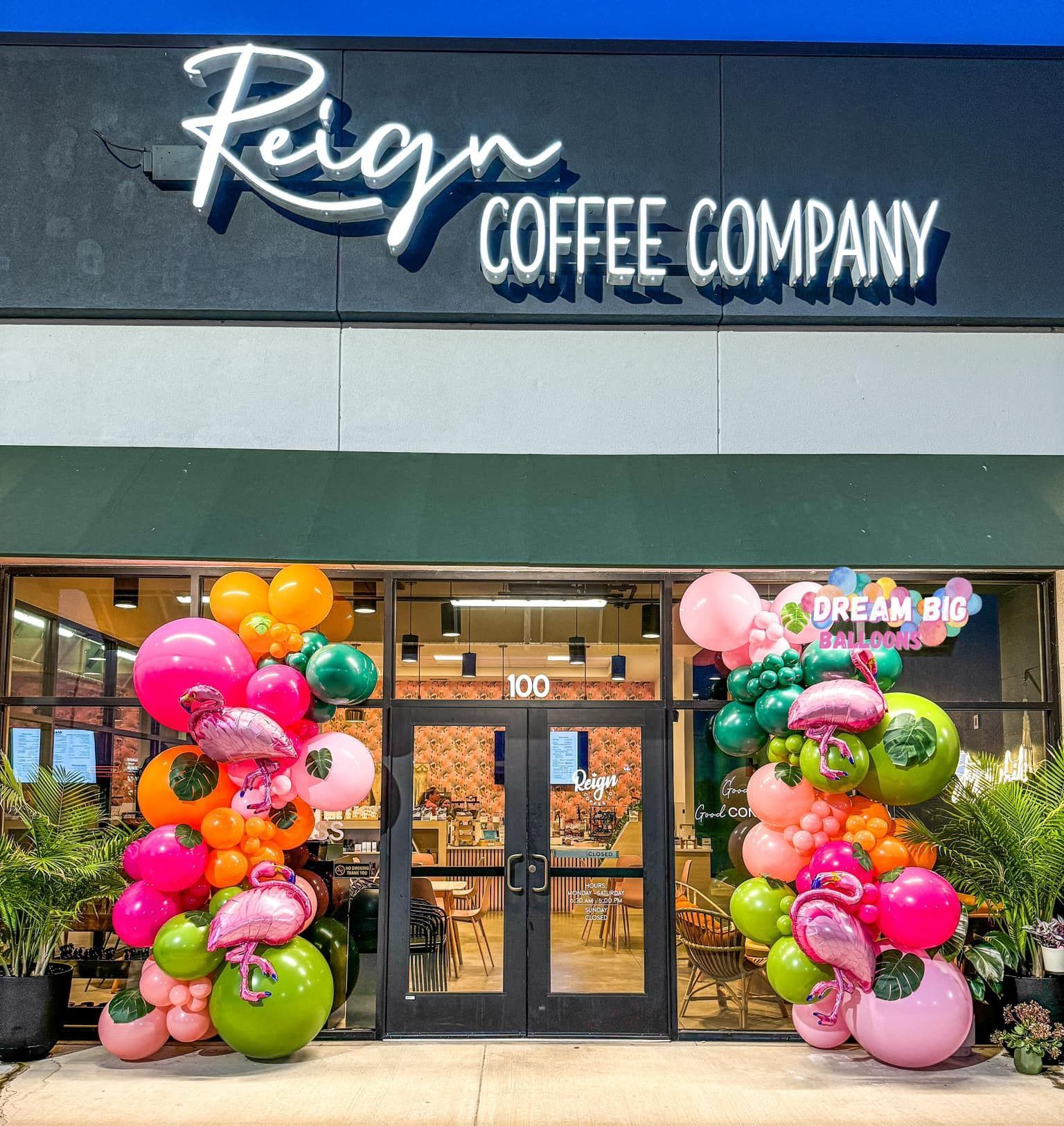 The front of a coffee shop with balloons in front of it.