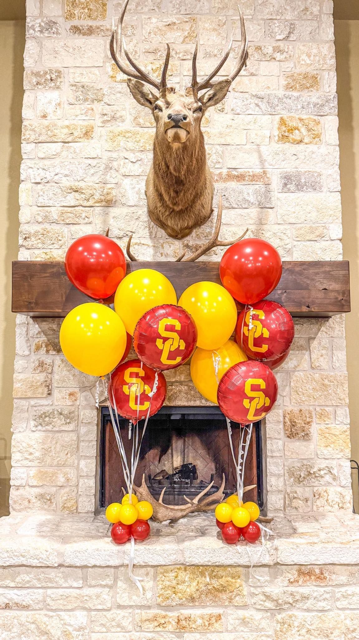 A fireplace decorated with SC balloons and a deer head.