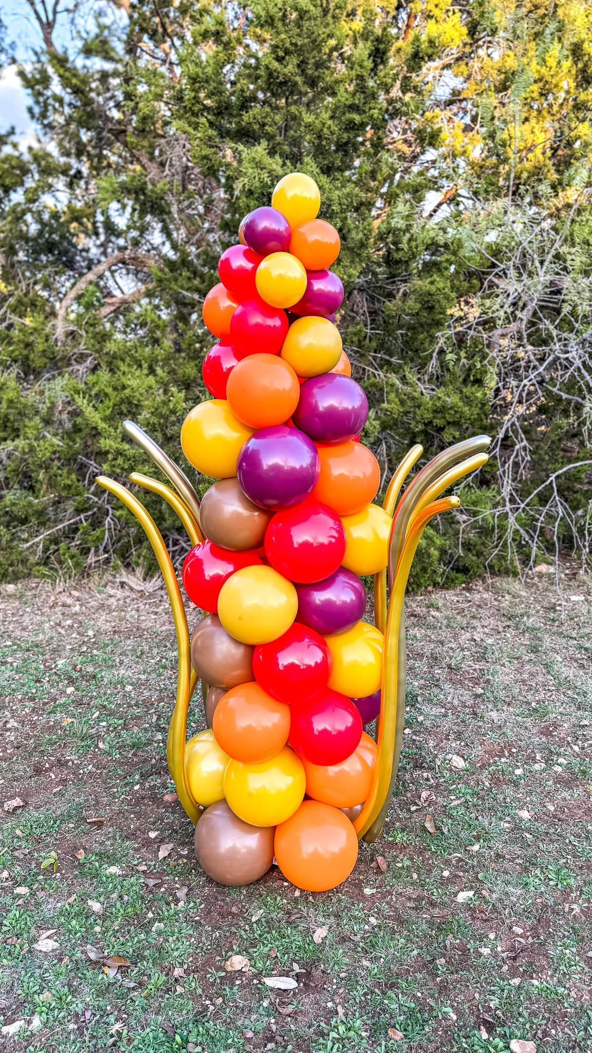 A bunch of balloons are stacked on top of each other in the shape of a corn on the cob.