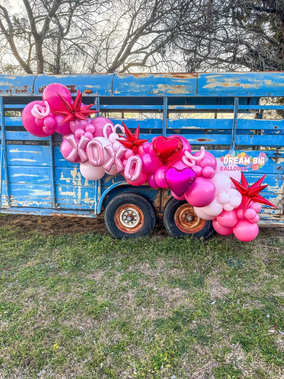 A bunch of pink balloons are sitting on top of a blue trailer.