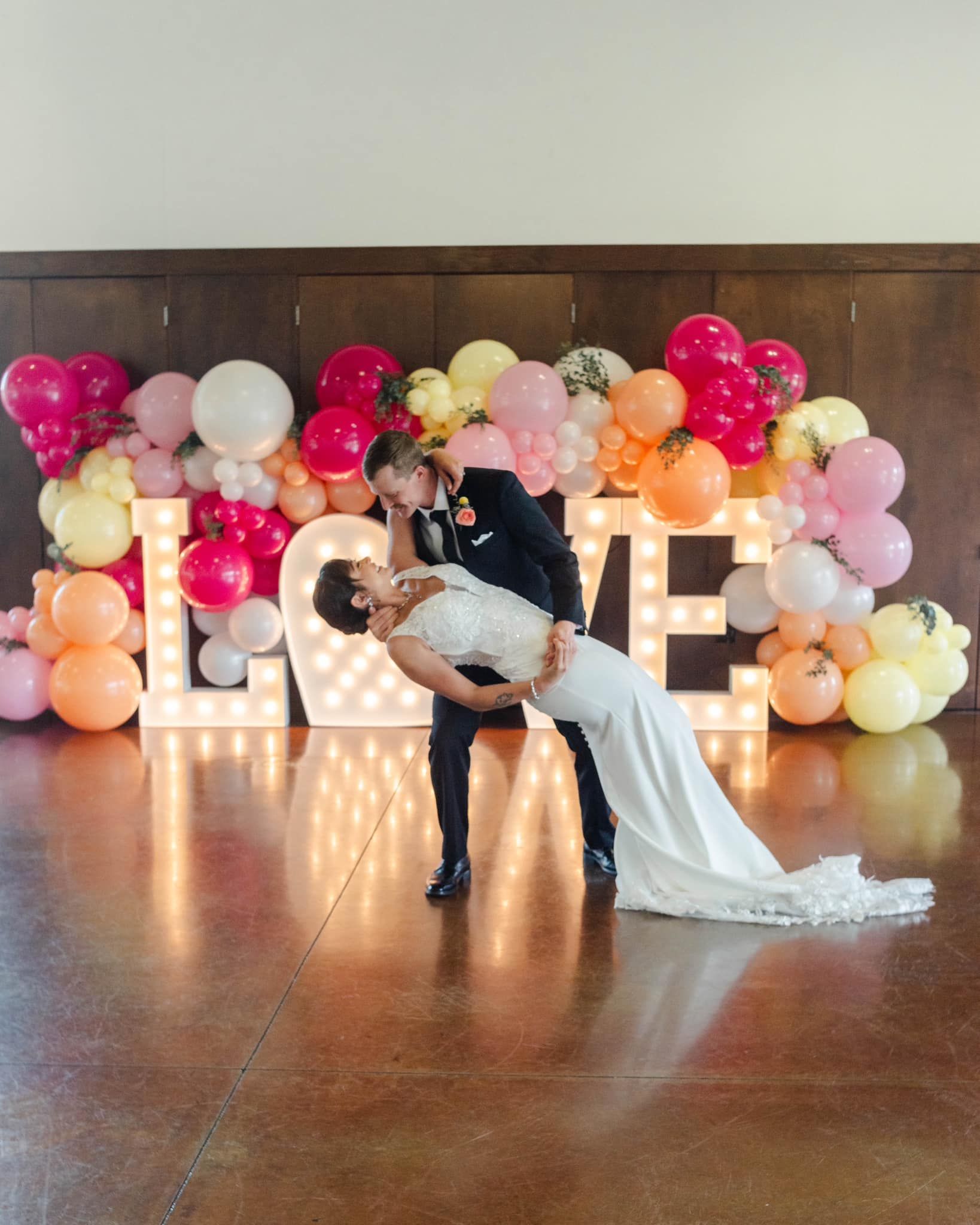 A bride and groom are posing for a picture in front of a love sign.