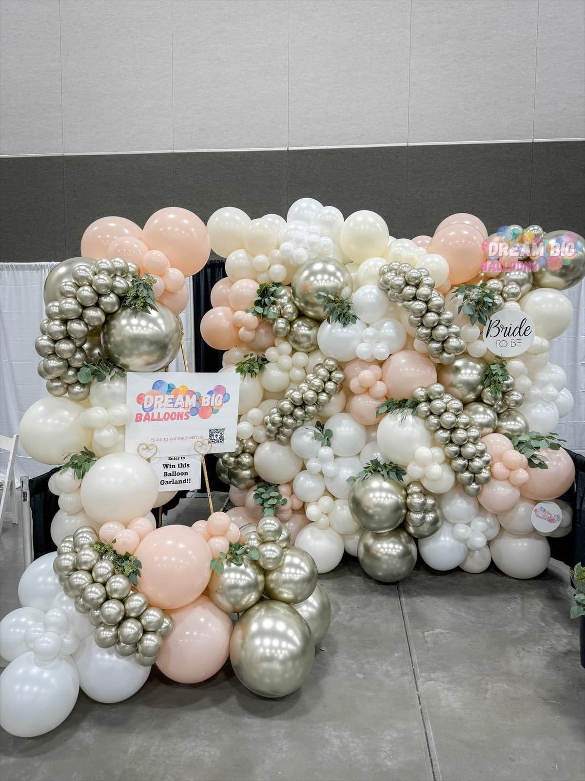 a wall of balloons sitting on top of a concrete floor