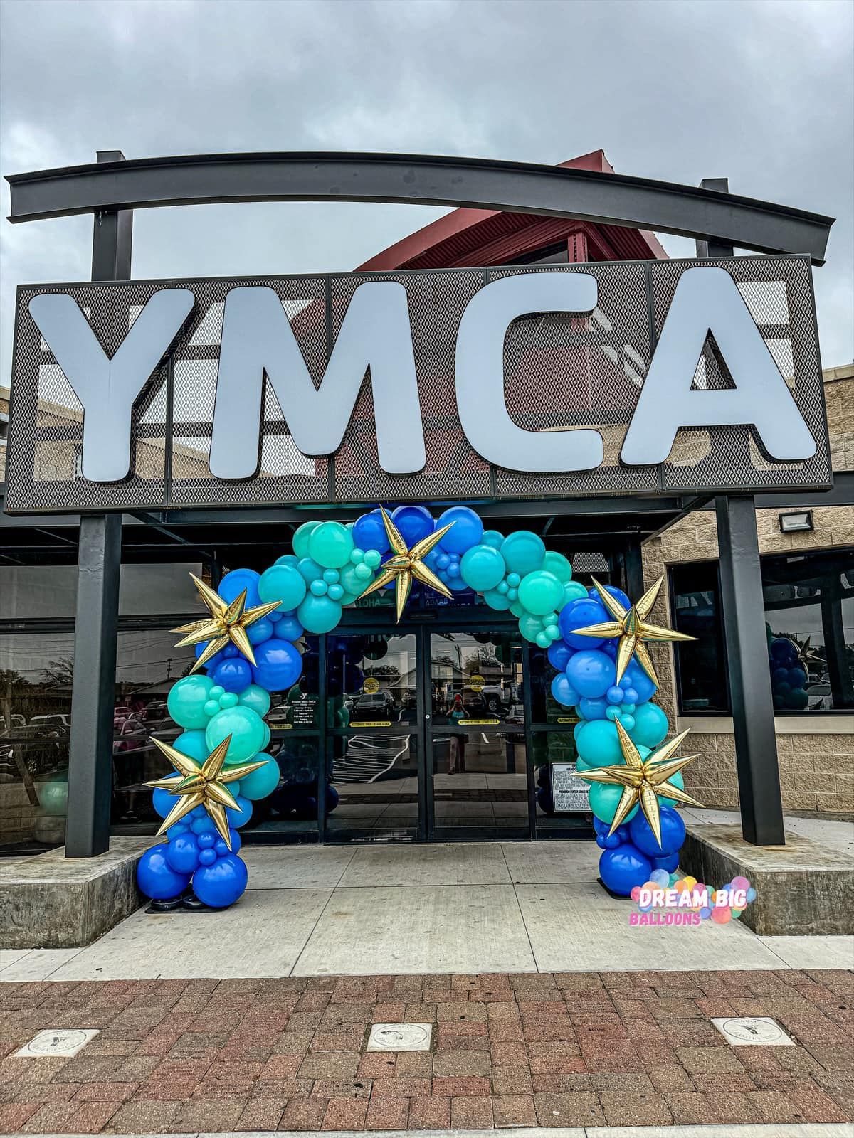 A balloon arch is in front of the ymca building.