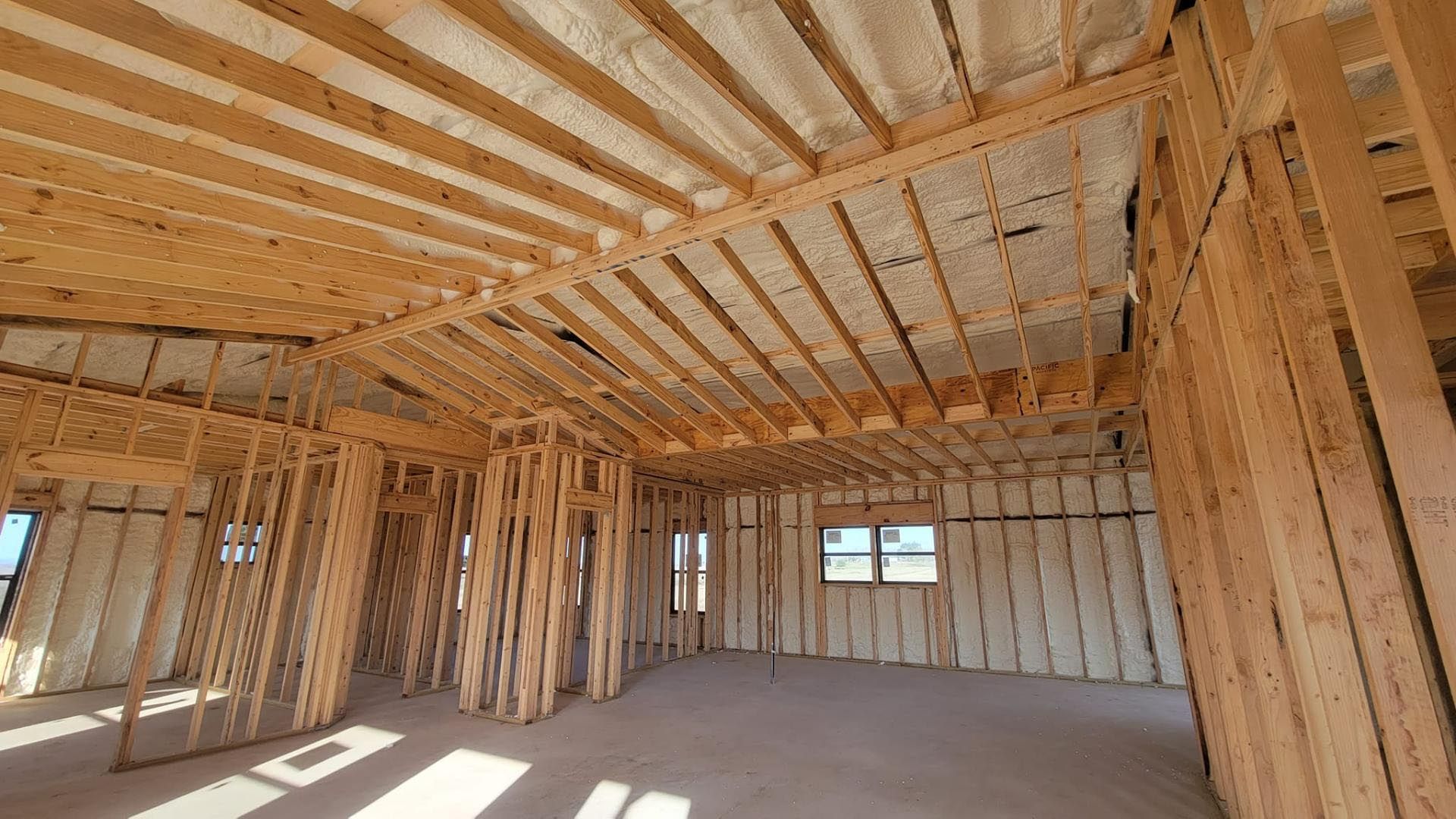 A room in a house under construction with wooden beams and insulation.