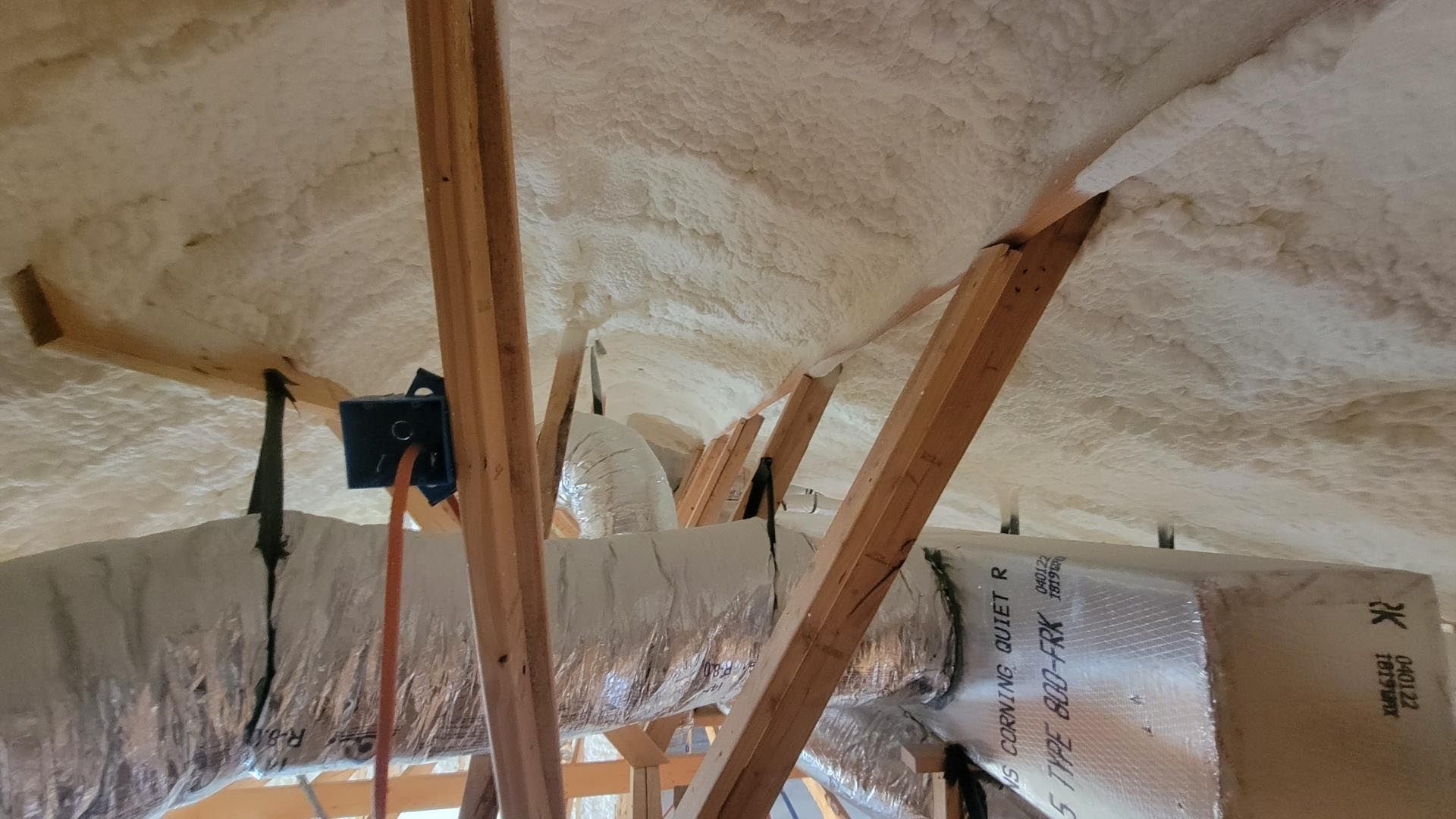 A ceiling with a lot of ducts and foam on it.