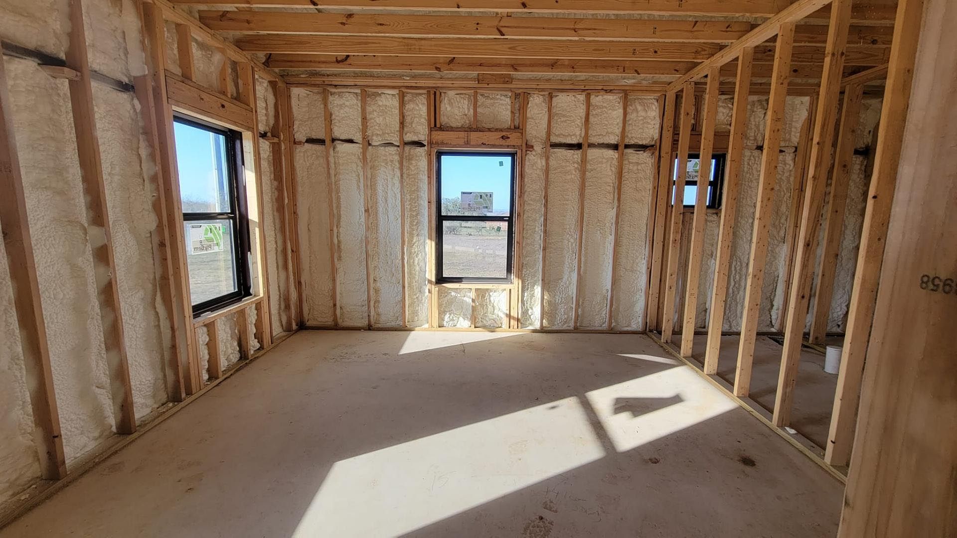 A room in a house under construction with a lot of insulation and windows.