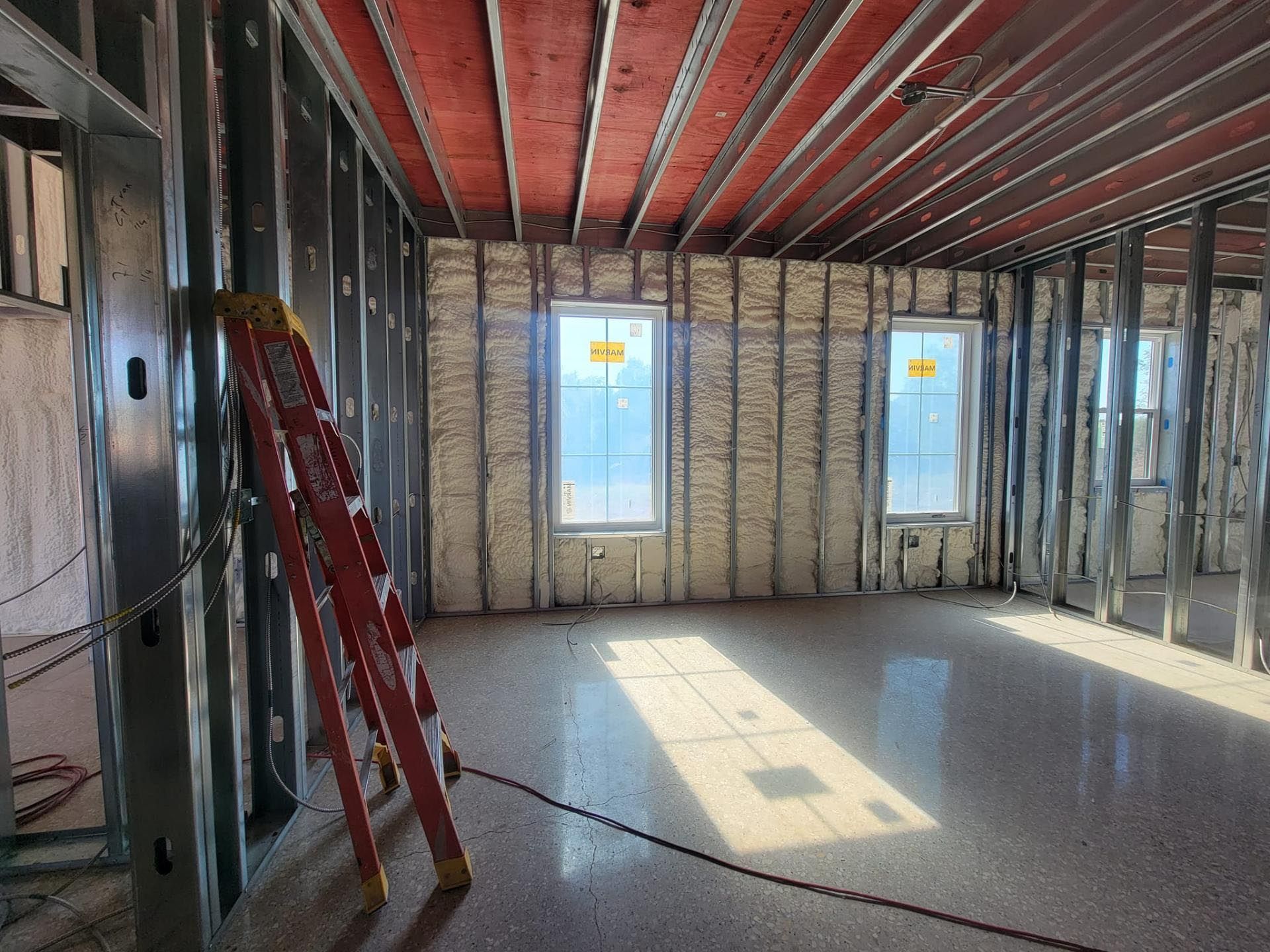 A ladder is sitting in the middle of a room under construction.