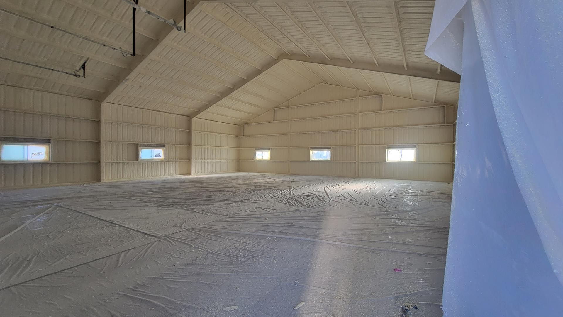 A large empty warehouse with a lot of windows and foam on the walls.