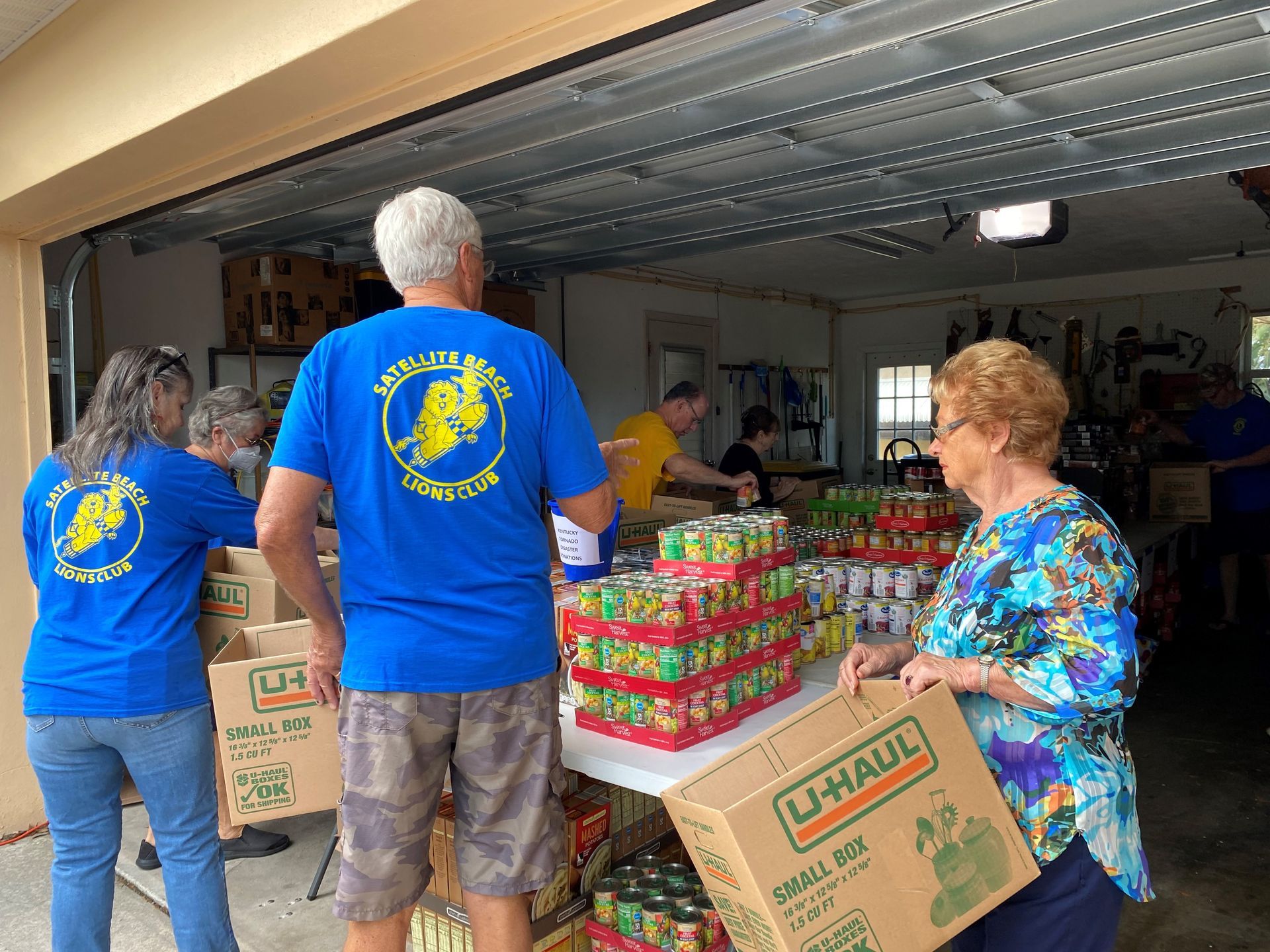 A group of people in blue shirts are working in a garage.