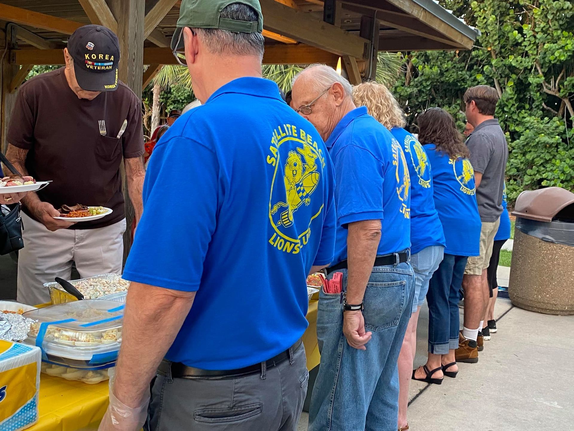 A group of people wearing blue shirts are standing in a line.