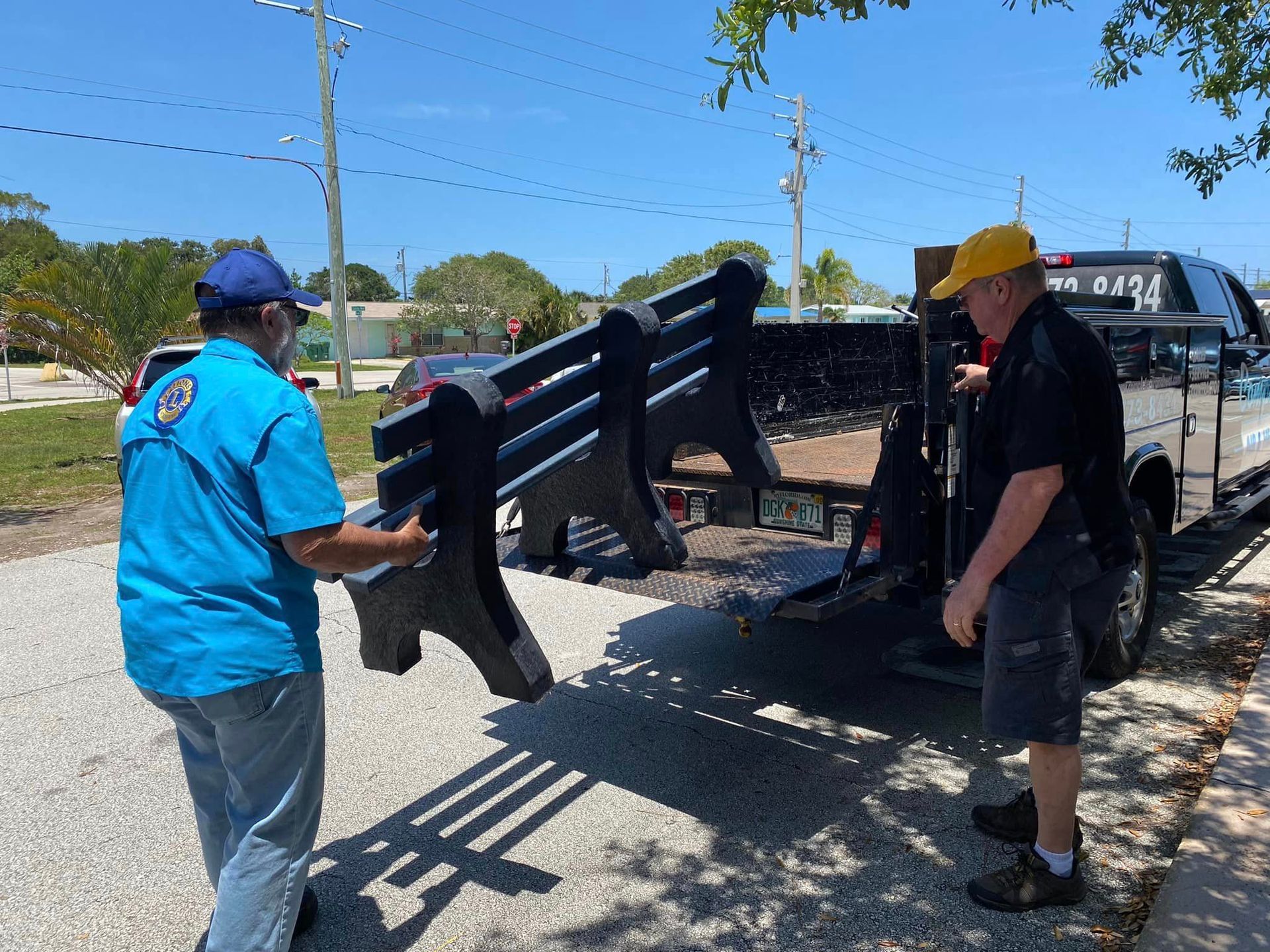 Two men are loading a bench onto a trailer.
