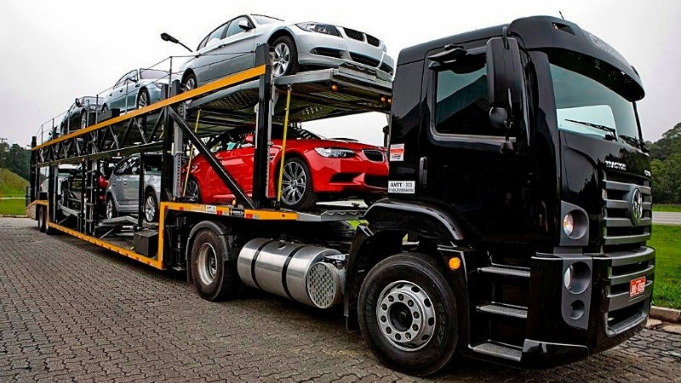 caminhão chegonha de cor preta carregado com veículos 