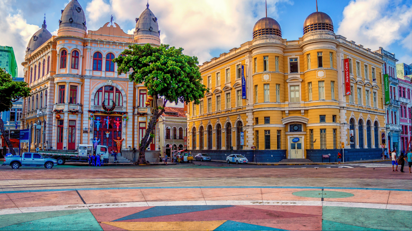 centro histórico de Recife: edíficio amarelo com cúpulas, prédios coloridos, sob céu azul.