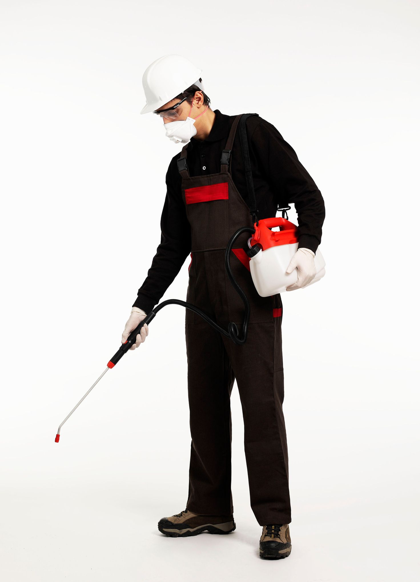 Man in overalls uses a sprayer on a white surface, showcasing bed bug pest extermination in Anderson, IN.