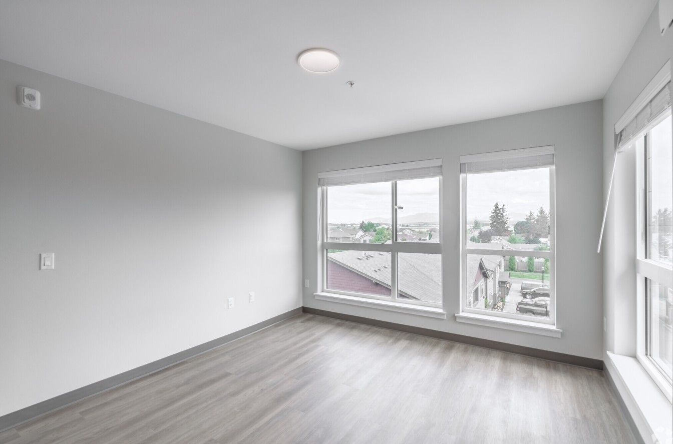 An empty room with a lot of windows and hardwood floors.