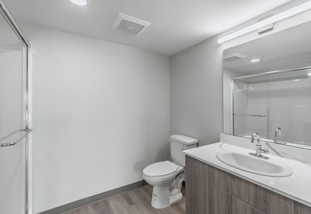 A bathroom with a toilet , sink and mirror.