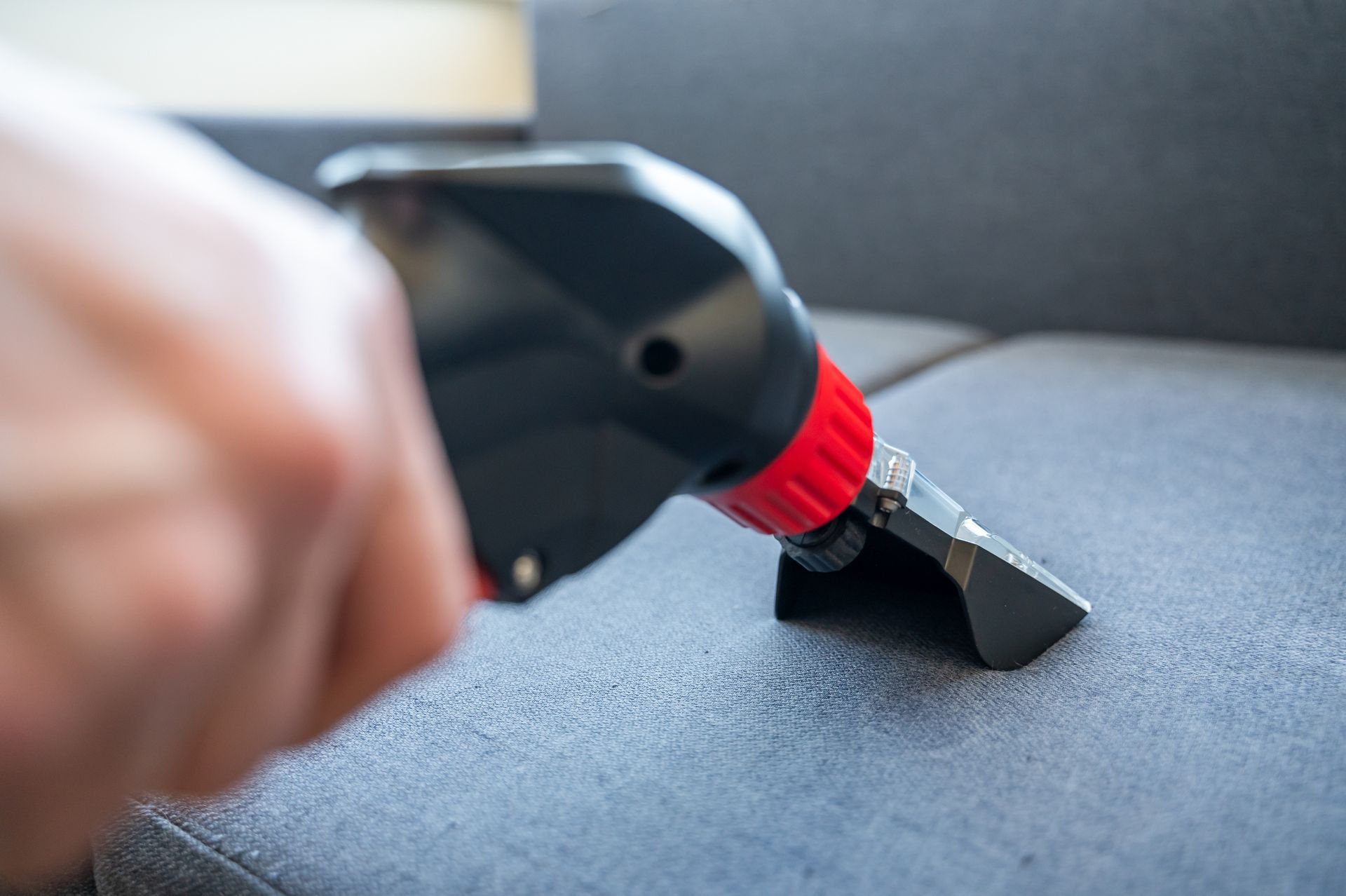Expert cleaner using a vacuum to clean upholstered furniture in commercial upholstery cleaning. Expert cleaner using a vacuum to clean upholstered furniture in commercial upholstery cleaning.
