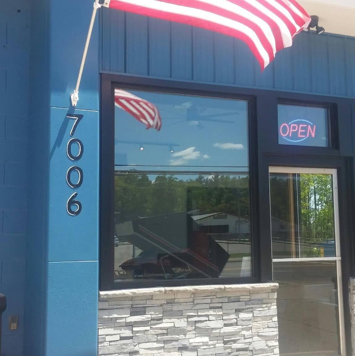 A building with a blue facade, large black-framed windows, an American flag, and 