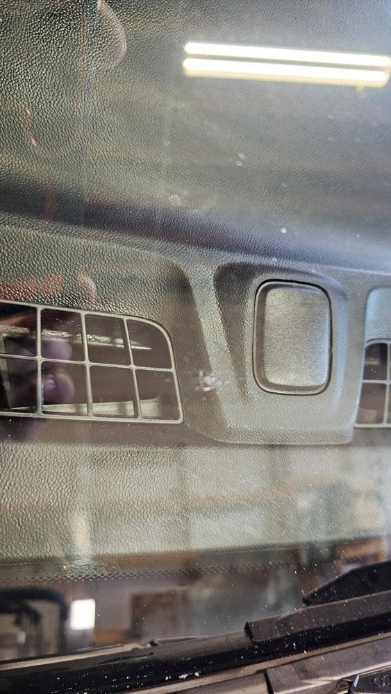 Interior dashboard with air vents, visible through a windshield.