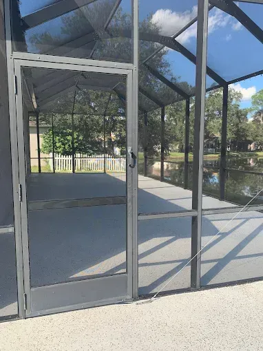 A screened in porch with a reflection of trees in the glass doors.