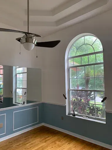 An empty room with a ceiling fan and a large window.