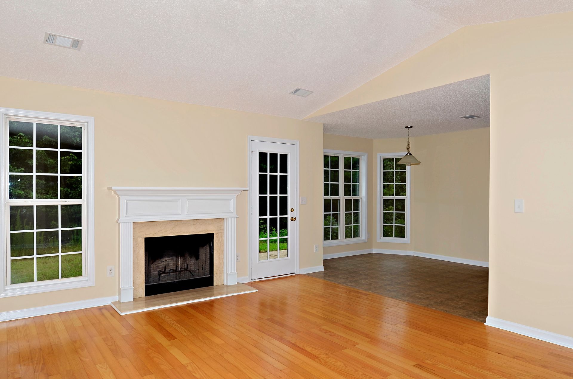 An empty living room with hardwood floors and a fireplace.