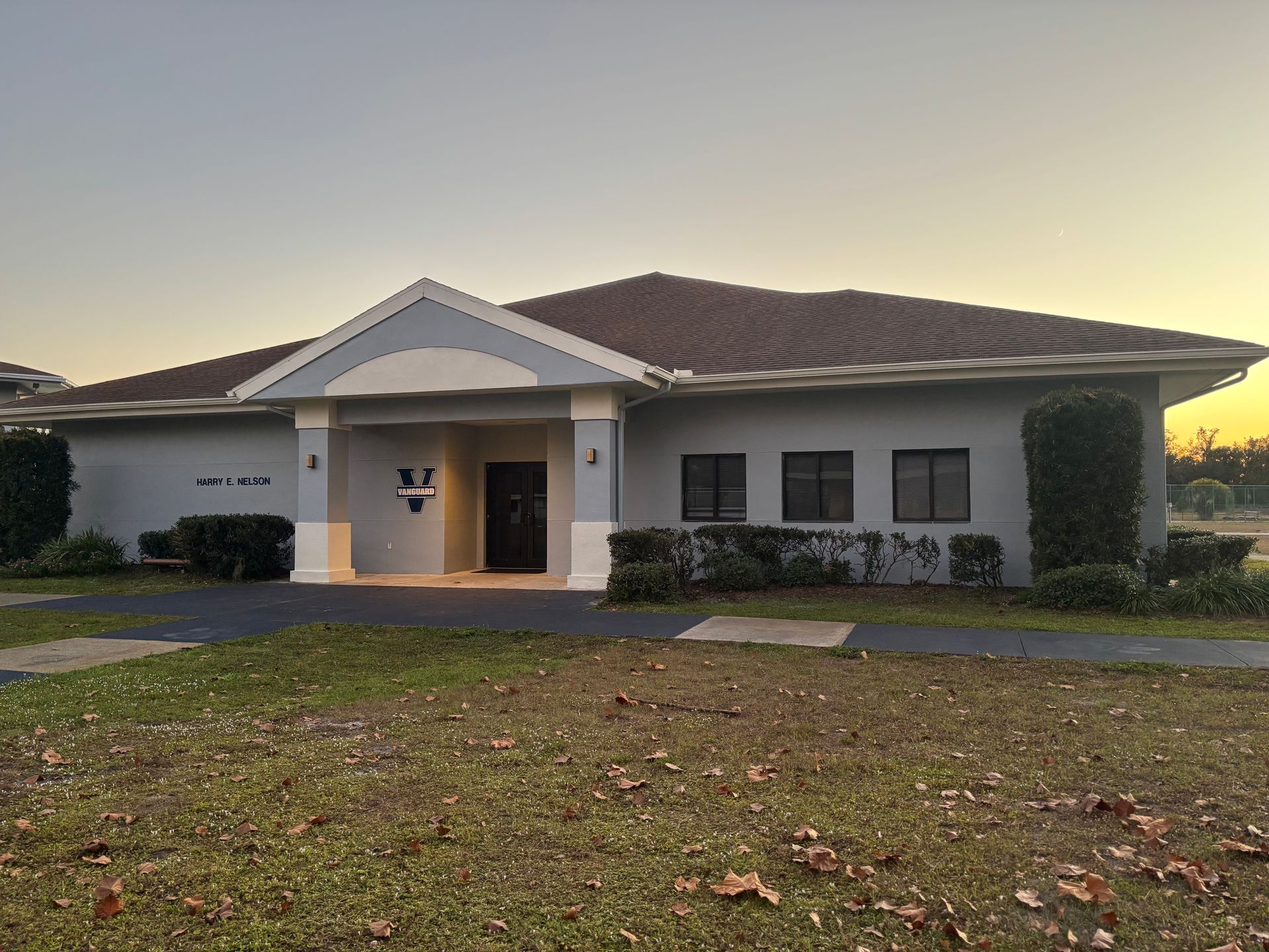 Building with a dark roof, gray walls, and a front porch. A logo is visible above the door.