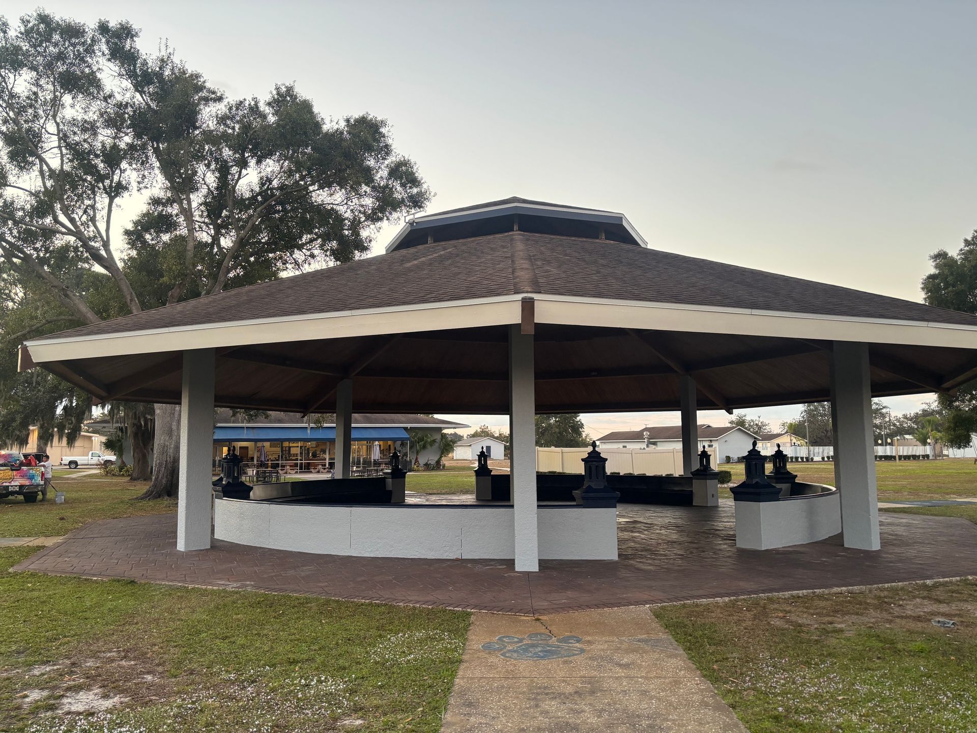 Pavilion with a brown roof and white support columns in a park.