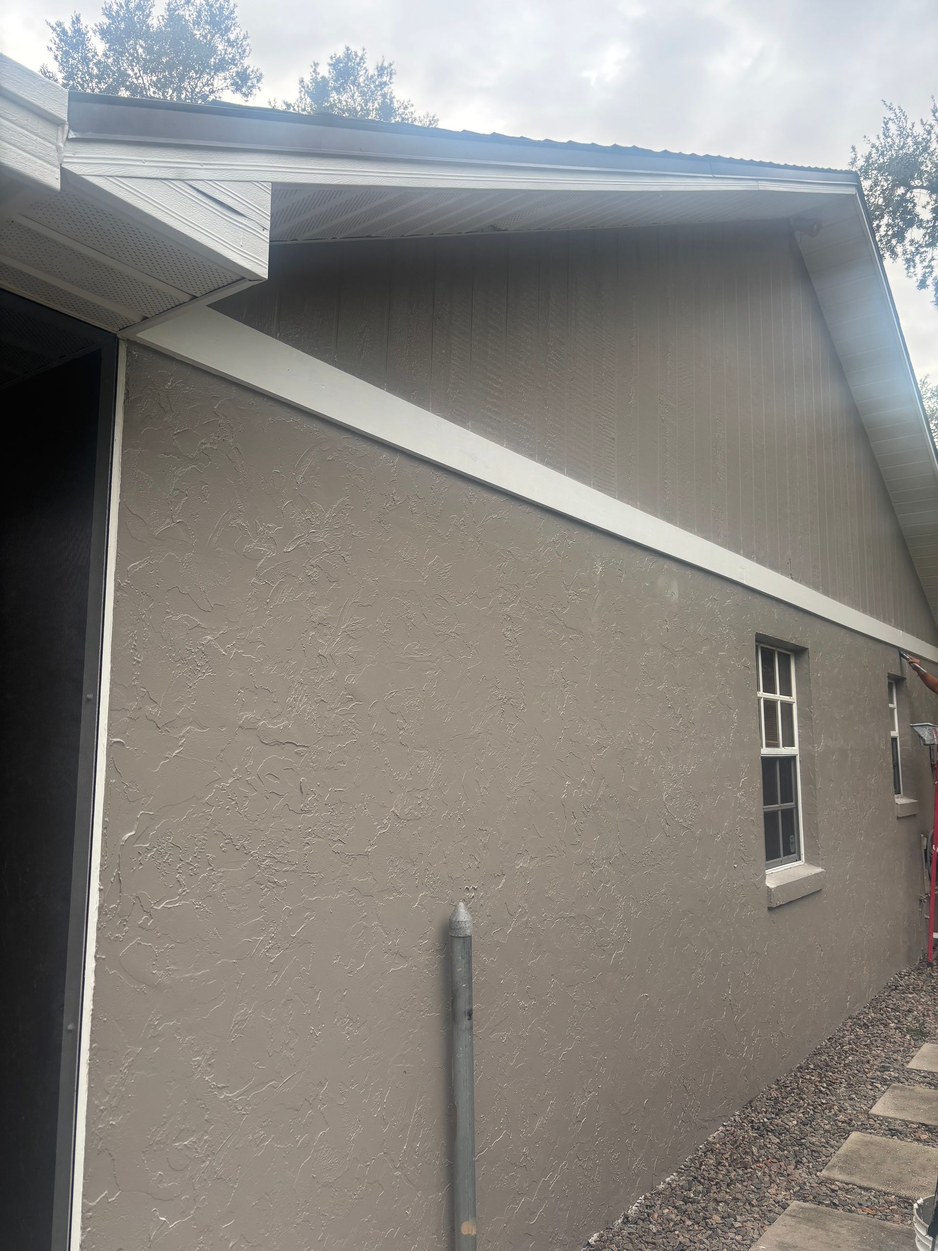 Tan stucco building exterior with white trim and a window.