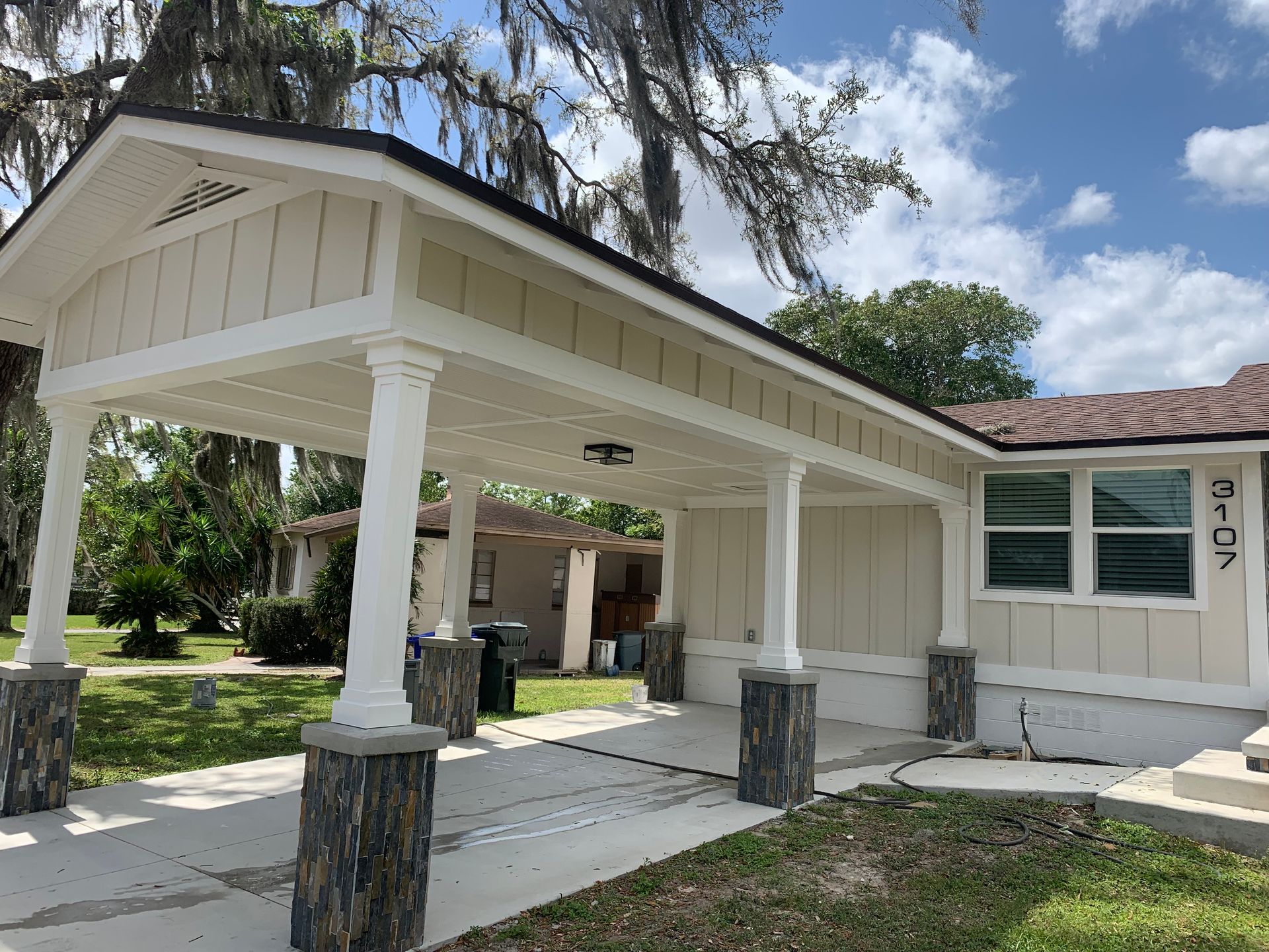 Beige carport with decorative pillars in front of a single-story house on a sunny day.