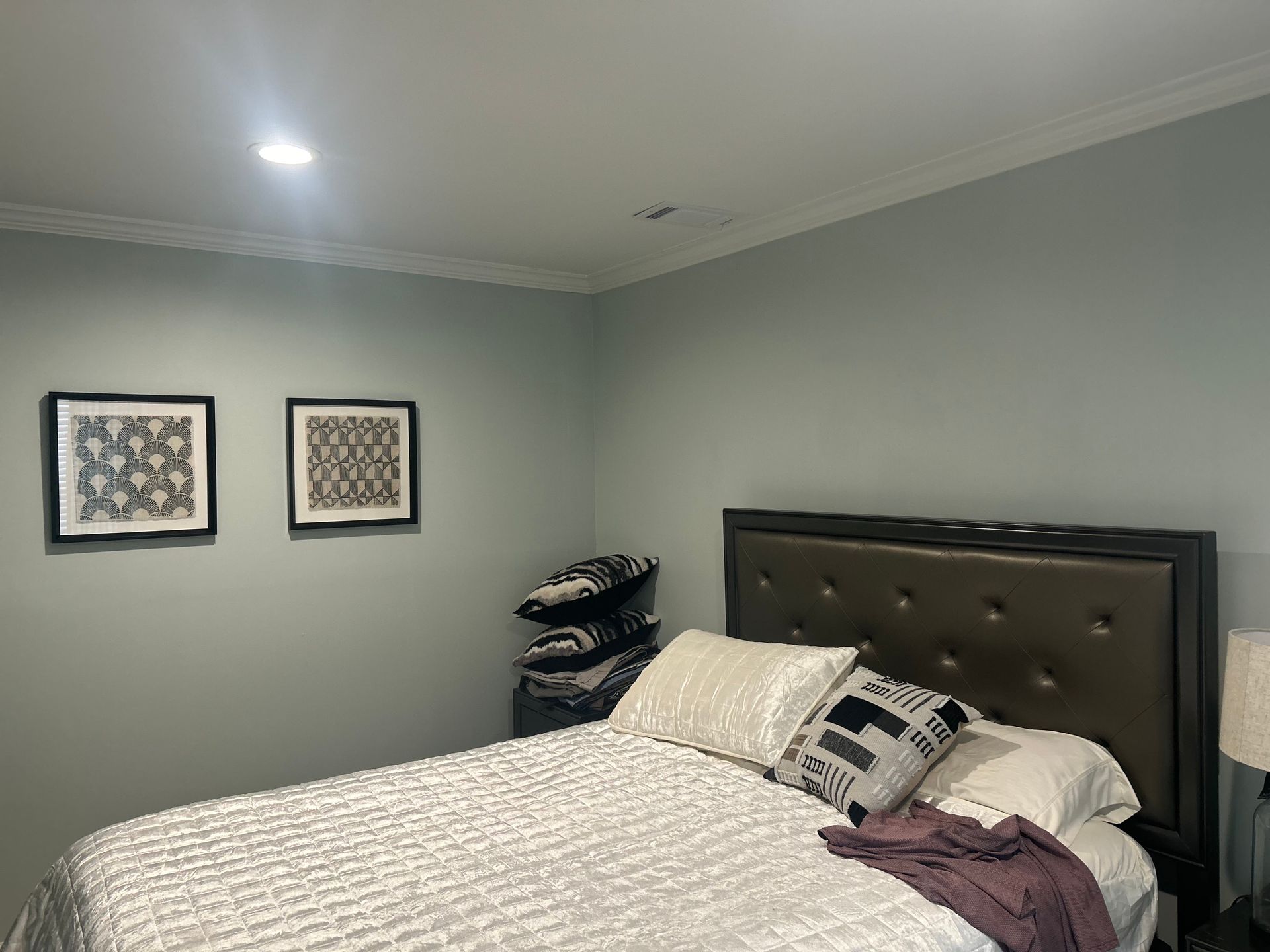 Bedroom with bed, artwork, pillows, and light blue walls.