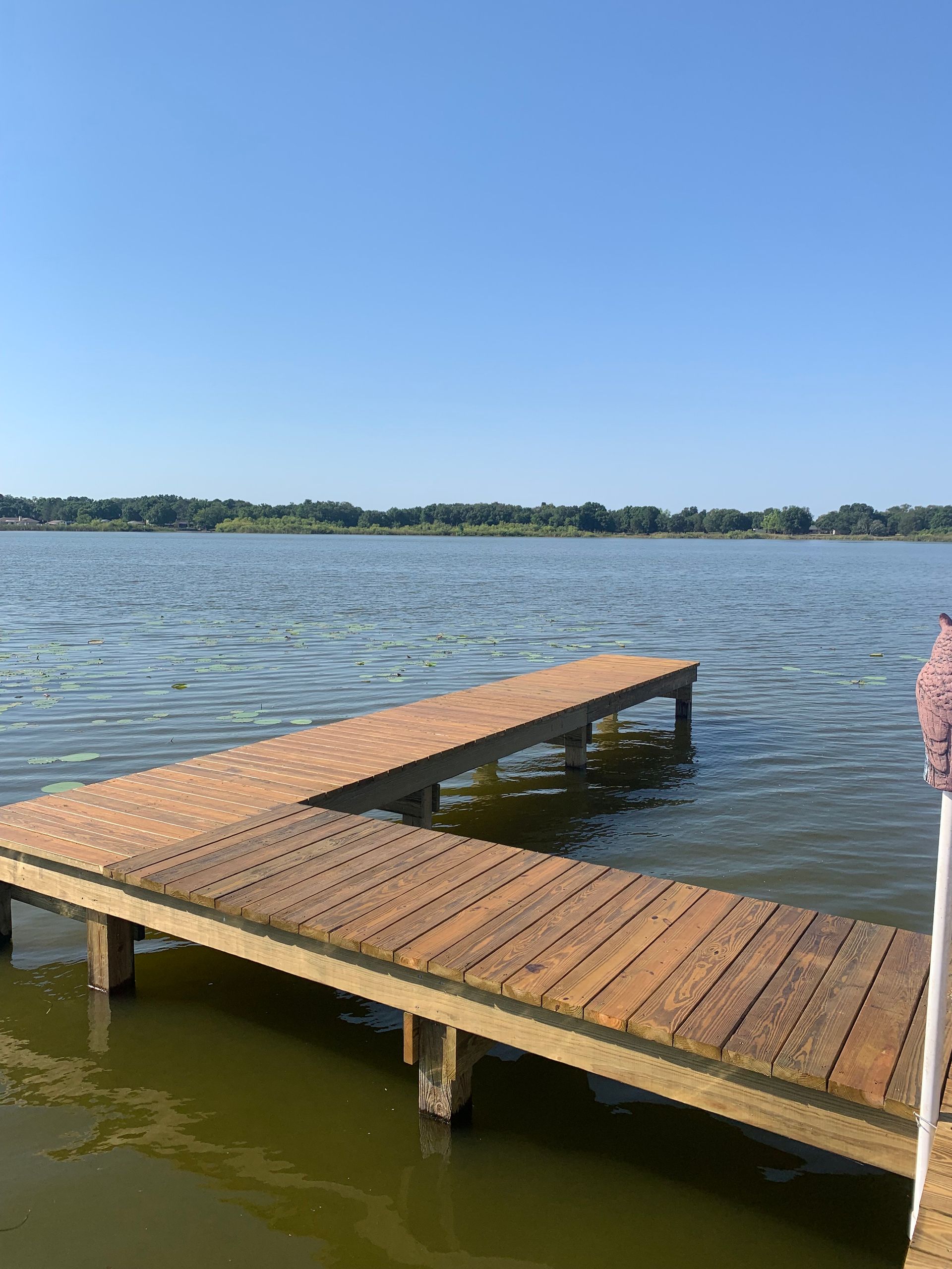 Wooden dock extending into a lake on a sunny day.