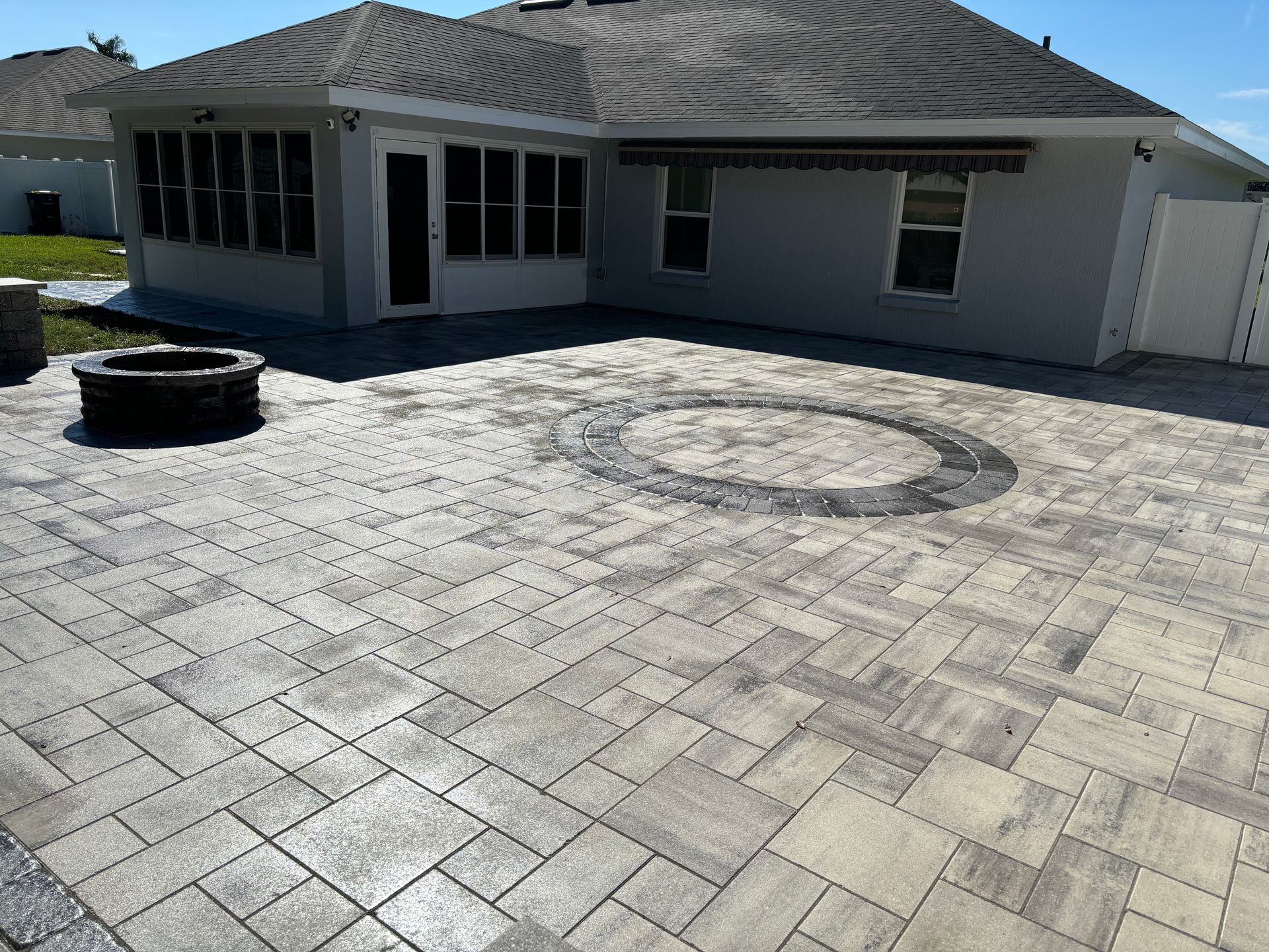Backyard patio with gray pavers, fire pit, and seating area.