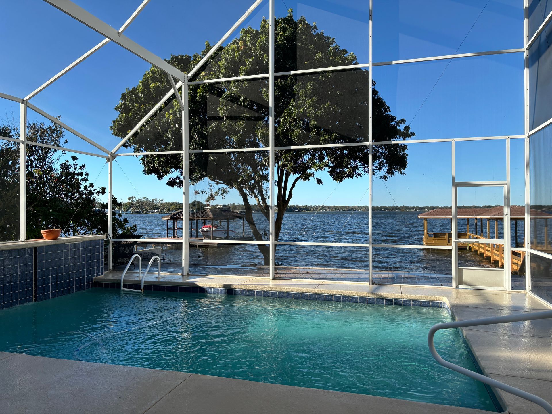 Swimming pool with a water view, enclosed by a white screened structure.