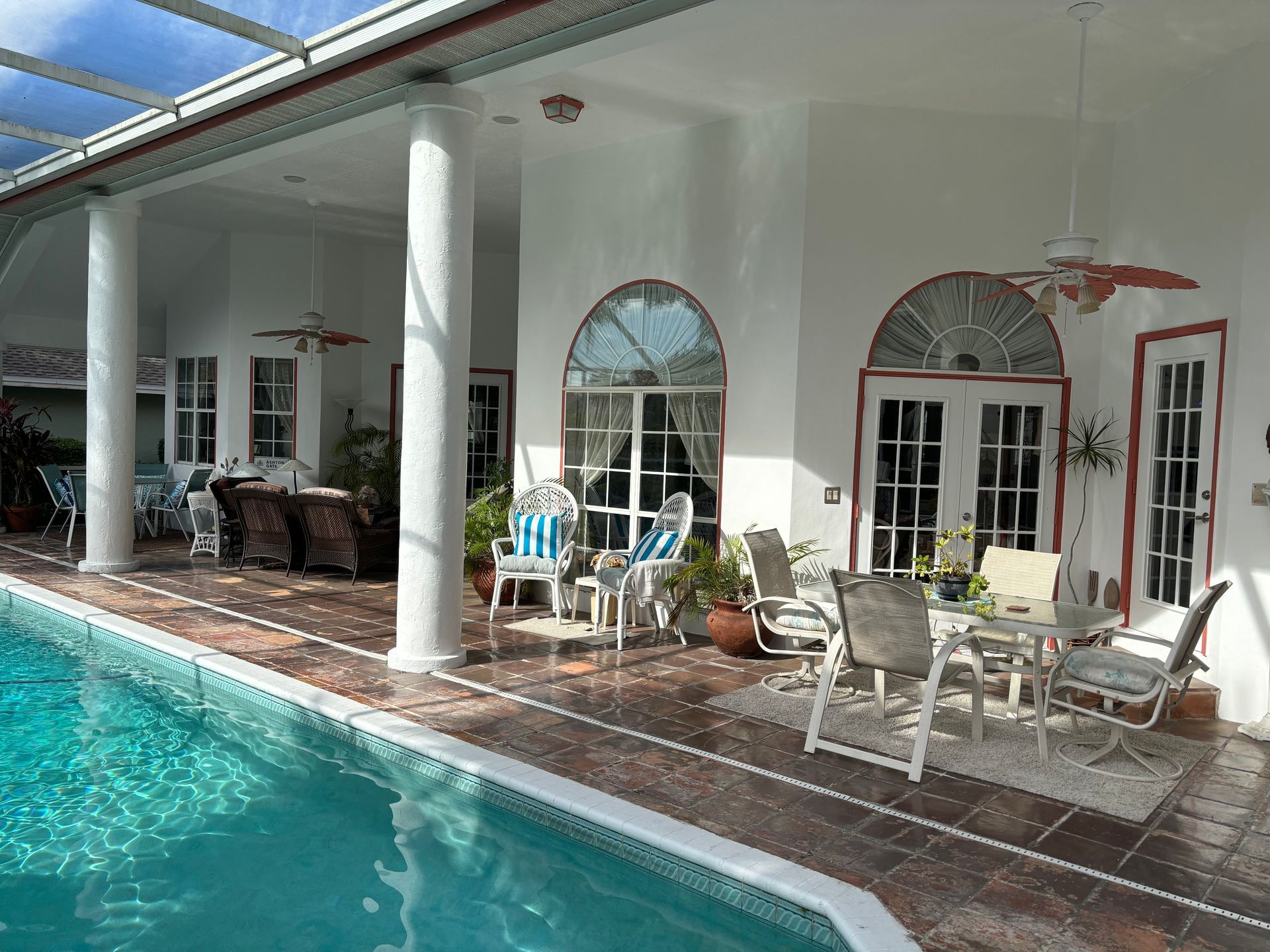 Poolside patio with white columns, furniture, and a turquoise pool.