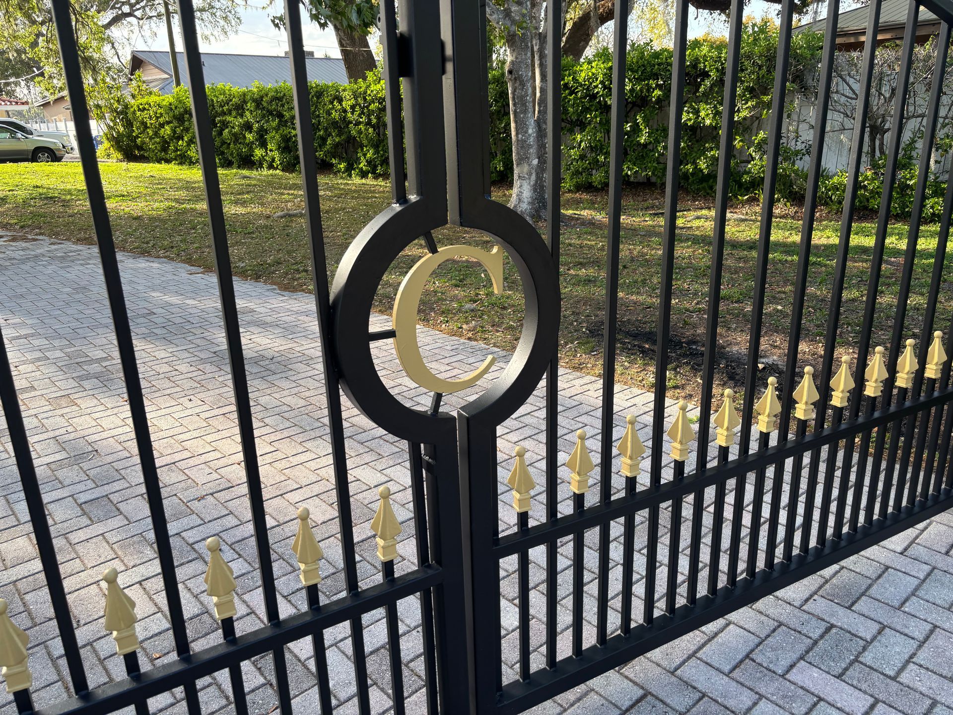 Black metal gate with gold accents, including a large letter 