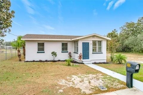 White bungalow with blue door, mailbox in front yard.
