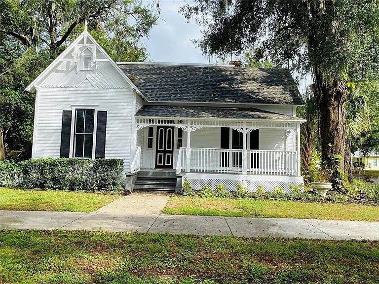 White Victorian house with black shutters, front porch, and walkway.
