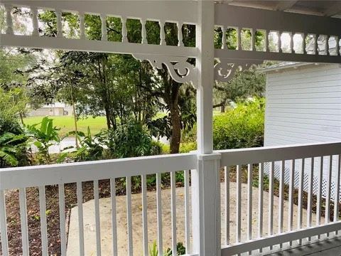 White porch railing with decorative trim overlooking greenery and a path.
